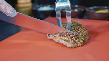 Chef slicing cooked pork steak at commercial kitchen