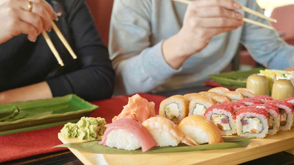 Young couple with chopsticks takes sushi from a plate in a japanese restaurant.