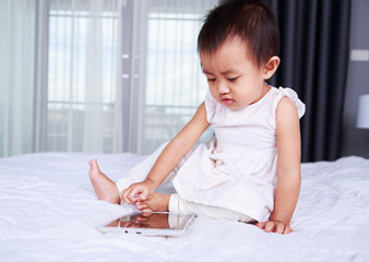 Fototapeta premium baby are looking to play and read tablet computer on bed