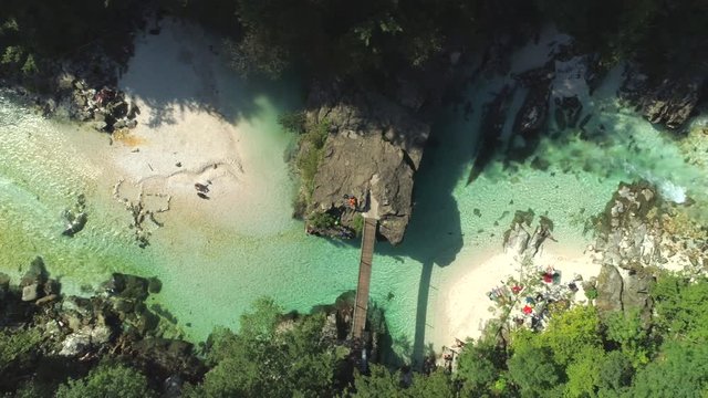 AERIAL TOP DOWN People enjoying summer vacation by riverside in nature. Tourists relaxing and exploring emerald Soca river in Slovenian national park. Turquoise river running trough lush green forest