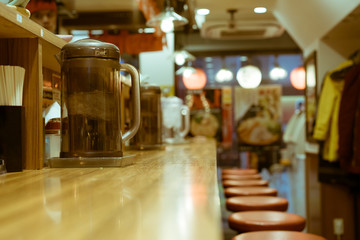 An empty bar with jugs of water inside a popular ramen shop in Shinjuku, Tokyo, Japan. A ramen shop is a restaurant that specializes in ramen dishes, the wheat-flour Japanese noodles in broth.