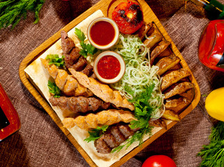 The meet and grilled vegetables on the table with tomato sauce and greens.