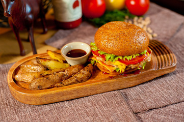 Juicy burger with French fries on a wooden dinette.