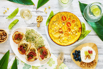 Frittata (omelet) with potato, tomato and pea sprouts, bruchetta, cheese plate and lemonade. Top view of brunch or lunch on a white table.