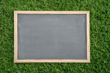 Abstract chalk blackboard with wood border frame on grass floor included copyspace ready used as...