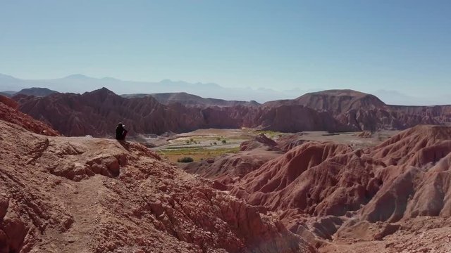 Aerial shot of female trekker standing at the cliff contemplating the horizon of the Atacama desert. 4k