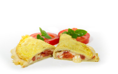 omelette made with beaten eggs stuffed with onion cheese and tomatoes on white background with sliced tomatoes and basil
