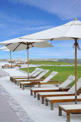 White color recliner beach seating with white parasol facing the sea front in Thailand