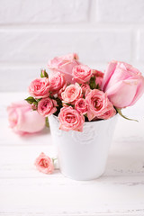 Pink roses flowers  in white pot against  white brick wall.