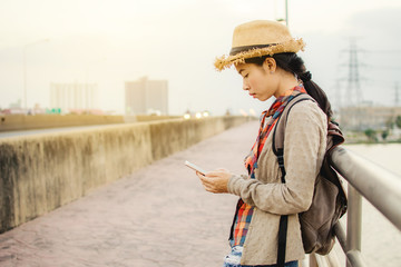 Asian women using smartphone during backpacker relax time on vacation hipster lifestyle, color style vintage tone