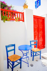 Outdoor cafe with blue chairs on street of typical greek traditional village on Mykonos Island, Europe
