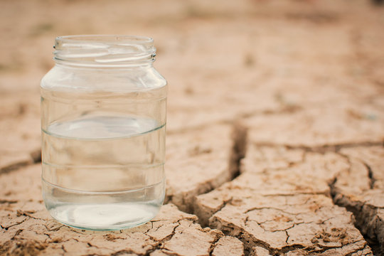 Glass jar on cracked dry ground, concept drought and water crisis