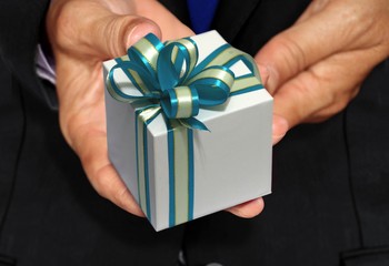 Hand holding white gift box with blue ribbon