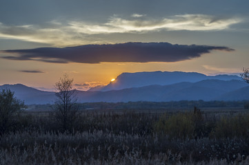 Fototapeta premium the setting sun above the hills, the far east