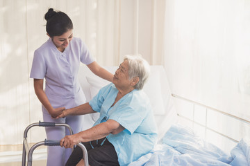 woman caregiver and elderly patient on examination couch. Happy nurse holding hand of senior to...