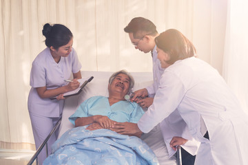 Fototapeta premium Elderly patient lying on bed with Doctors and nurse consulting for encouraging in treatment at hospital ,Health care and people concept