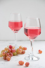 Pink wine and a grape on the white background