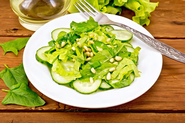 Salad from spinach and cucumbers with cedar nuts on table