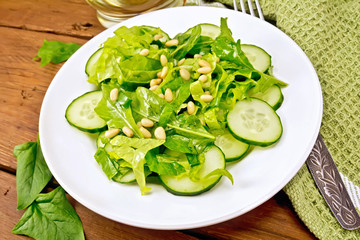 Salad from spinach and cucumbers with fork on table