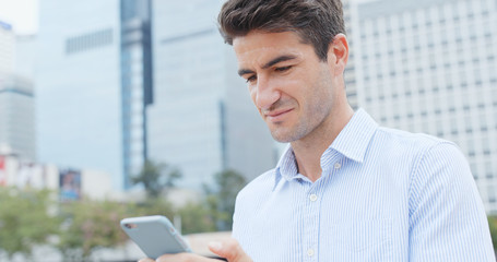 Caucasian businessman look at mobile phone in city