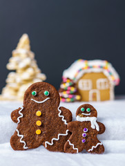 home made delicious traditional gingerbread village and gingerbread man family black background.