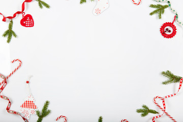 Christmas holiday composition. Festive creative red pattern, xmas handmade decor holiday with ribbon, Christmas candy canes, gift, christmas tree and red decorations on white background.