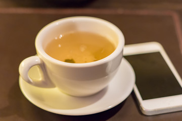 cup of green tea nd white phone on table