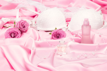 Perfumes with roses and women underwear on pink silk