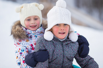 Winter portrait of two girls girlfriends riding on tubing