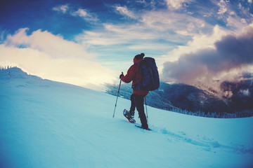 A man in snowshoes in the mountains.
