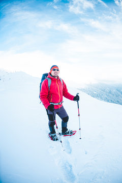 A man in snowshoes in the mountains.