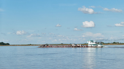 The Irrawaddy river near Mandalay. A barge being pushed by a boat.