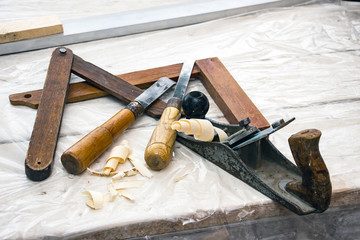 A carpenter's tool. On the table is a square, chisels and planer with shavings