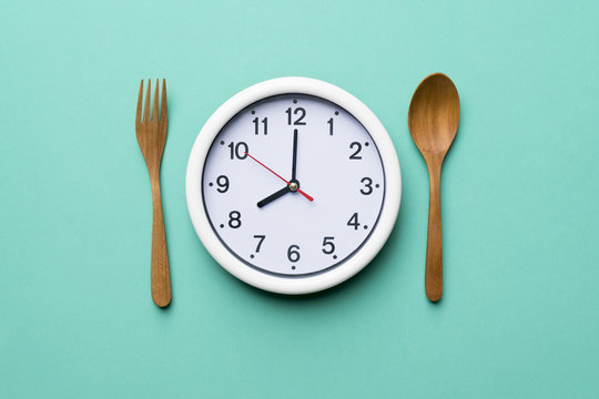 Food clock with wood spoon and fork. Healthy food concept on green background