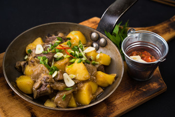 freshly cooked meat and potatoes in metal pan on cutting board