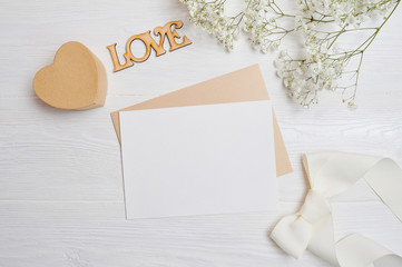 Mock up letter with a love box in the shape of a heart lies on a wooden white table with gypsophila...