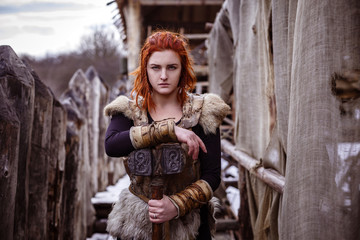 Viking woman with hammer in a traditional warrior clothes.