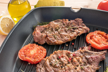 Grilled steak on grill pan with tomatoes and spices close-up