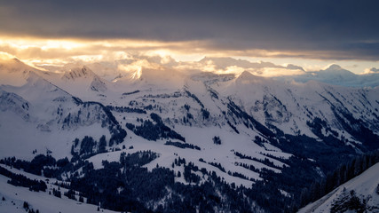 Fototapeta na wymiar Early morning at the Chlushuette in the Swiss Alps. Sunrise over the Eiger, Jungfrau and Mönch mountain area. Sun breaking through after a heavy snow storm on a winter day in just before Christmas