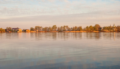 village with church on the shore of the lake dawn