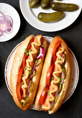 Hot dogs with tomato, marinated cucumbers, onion