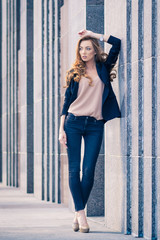 Outdoors fashion portrait of trendy pretty girl posing on the wall background.