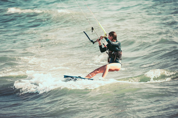 Kite surfing girl in sexy swimsuit with kite in blue sea riding waves with water splash. © Mediteraneo
