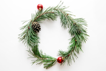 Traditional Christmas wreath from a green pine tree with red balls on a white background, flat, top view
