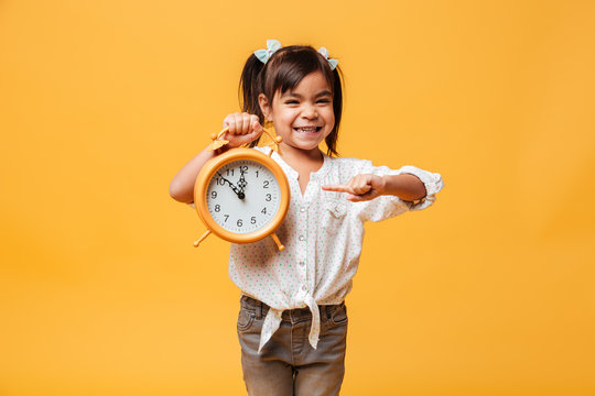 Smiling little girl child holding clock alarm.