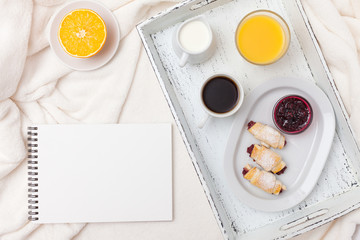 Freshly baked croissant, orange juice, jam, cup of black coffee on white wooden tray on plaid. Homemade cookie. Fresh pastries for breakfast. Delicious dessert. Closeup photography. Horizontal banner