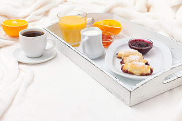 Freshly baked croissant, orange juice, jam, cup of black coffee on white wooden tray on plaid. Homemade cookie. Fresh pastries for breakfast. Delicious dessert. Closeup photography. Horizontal banner