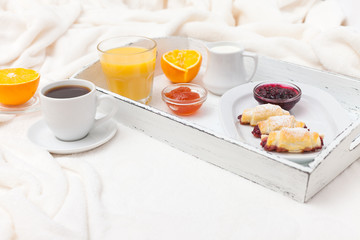 Freshly baked croissant, orange juice, jam, cup of black coffee on white wooden tray on plaid. Homemade cookie. Fresh pastries for breakfast. Delicious dessert. Closeup photography. Horizontal banner
