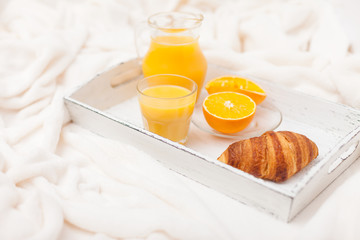 Freshly baked croissant, orange juice, jam, cup of black coffee on white wooden tray on plaid. Homemade cookie. Fresh pastries for breakfast. Delicious dessert. Closeup photography. Horizontal banner