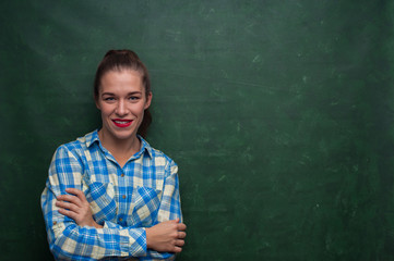 Portrait of an attractive young female student in checkered shirt on green background
